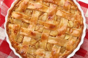 Delicious homemade apple pie in baking dish on checkered napkin, top view