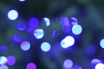 Beautiful blurred Christmas lights on color background, closeup. Bokeh effect