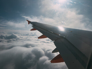 Obraz premium Airplane wing flying above clouds with sun rays