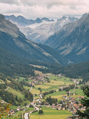 Obraz premium Alpine valley village with winding river and glacier