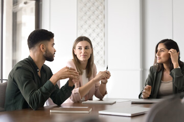Three professionals engaged in brainstorming session, focused conversation at table