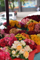Vibrant display of assorted roses in various colors, arranged in baskets at a market stall, showcasing the beauty and diversity of floral arrangements for decoration and gifting