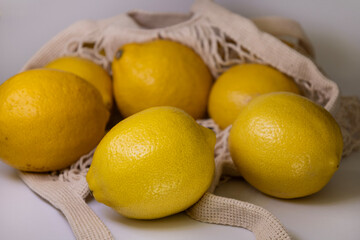 Fresh Yellow Lemons in Trendy Mesh Bag – Flat Lay on White Background with Copy Space