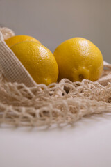 Premium Food Styling with Fresh Yellow Lemons in Mesh Bag – Flat Lay on White Background