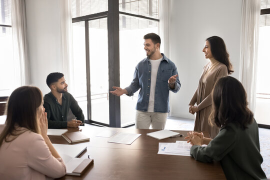 Man speaking to group of seated colleagues in modern office
