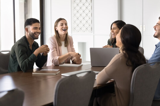 Fototapeta Diverse coworkers laughing together during team meeting