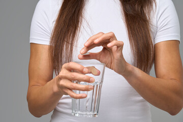 Close-up of woman dropping vitamin tablet into glass of water during daily supplement routine