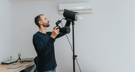 A photographer setting up his equipment in a bright home studio environment.