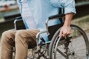 Care and resilience as a grandpa sits in a wheelchair beside a sunlit park showcasing family love and accessibility