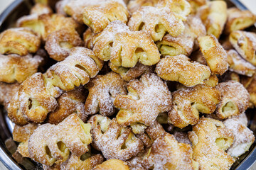 A heaping plate of golden puff pastries dusted with powdered sugar, each with visible slits and a sweet filling peeking through the flaky layers