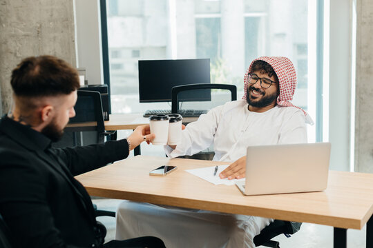 Diverse business partners toasting coffee in office