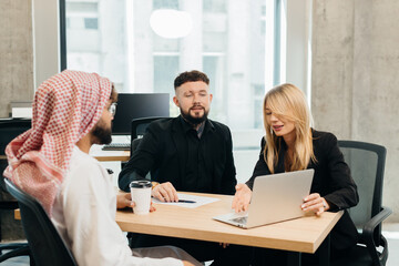 Diverse business team collaborating on laptop in office meeting
