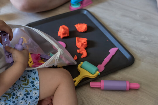 Children playing with modeling clay and educational toys on the floor. Close-up of young children using colorful modeling clay and plastic tools for creative play on the floor.