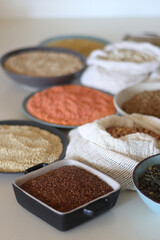 Bowls and bags full of various healthy grains and legumes. Selective focus.