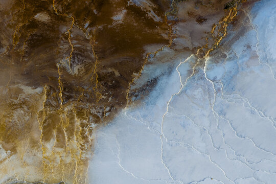 Aerial view of earth's canvas painted with strokes of rust and ice, where golden veins trace paths through a landscape of contrasting textures, Geothermal Areas, Iceland.