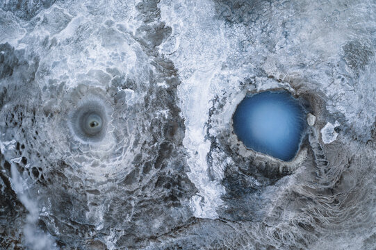 Aerial view of the geothermal area's otherworldly textures and vivid blue pools against the pale, cracked earth create a stunning mosaic of nature's artistry, Geothermal Areas, Iceland.