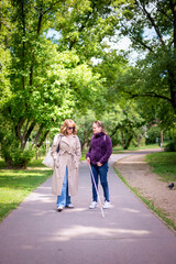 Fototapeta premium A visually impaired woman with white cane walking with her female friend in the city park
