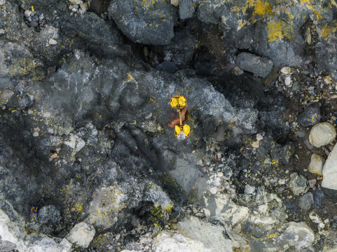 Aerial view of rugged terrain with sulfur deposits and volcanic rocks creating a stark, textured landscape, Mount Ijen, East Java, Indonesia.