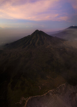 Aerial view of the rugged, mountainous landscape with a dramatic peak piercing through the soft hues of the twilight sky., Mount Ijen, East Java, Indonesia.