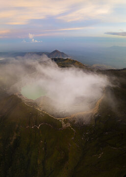 Aerial view of the Ijen volcano crater shrouded in ethereal white clouds, a dramatic spectacle of nature's raw beauty, Mount Ijen, East Java, Indonesia.