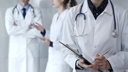 Medical professional writing on clipboard with stethoscope, a doctor and female assistant collaborating in a clinic, discussing patient data and healthcare information - Powered by Adobe