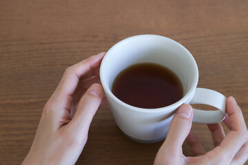 紅茶が入ったマグカップを持つ手元