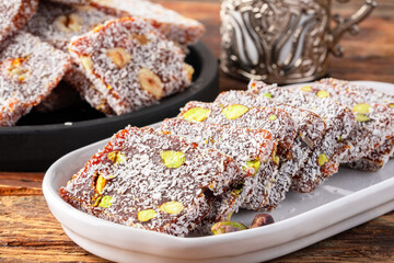 Turkish delight cezerye with pistachio or hazelnut on wooden background. Cezerye, a traditional dessert from the Mersin region