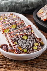 Turkish delight cezerye with pistachio or hazelnut on wooden background. Cezerye, a traditional dessert from the Mersin region