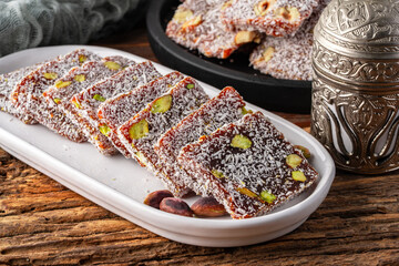 Turkish delight cezerye with pistachio or hazelnut on wooden background. Cezerye, a traditional dessert from the Mersin region