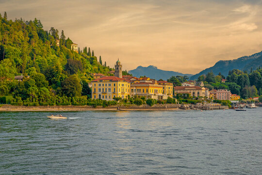 Sunset view of Bellagio from a ferry on Lake Como, with golden light reflecting on the water, charming lakeside buildings, and surrounding mountains creating a magical evening scene