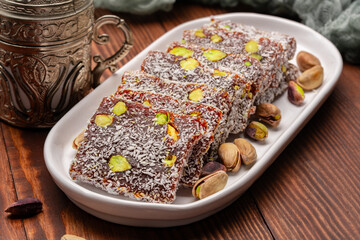 Turkish delight cezerye with pistachio or hazelnut on wooden background. Cezerye, a traditional dessert from the Mersin region