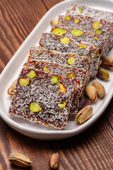 Turkish delight cezerye with pistachio or hazelnut on wooden background. Cezerye, a traditional dessert from the Mersin region