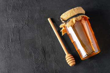 Honey jar and honey dipper on black background	
