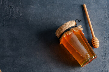 Honey jar and honey dipper on black background	

