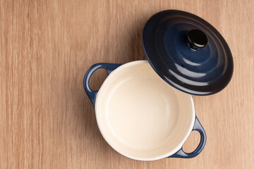 close up of a empty mini crock pot, in dark blue on a wooden table background 