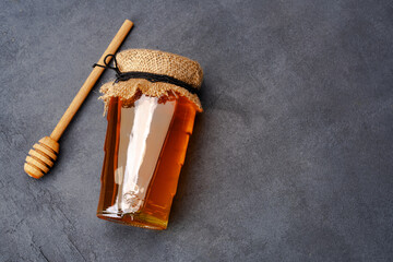 Honey jar and honey dipper on black background	

