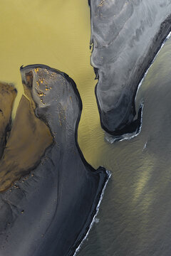Aerial view of striking black sands meeting the golden glacial waters, South Coast, Iceland.