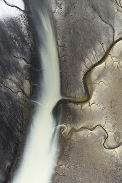 Aerial view of braided river systems carve intricate paths through the stark, contrasting landscapes of South Coast, Iceland.