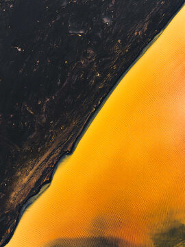 Aerial view of the striking contrast between the dark, textured earth and the vibrant, sun-drenched sands creates a mesmerizing landscape, South Coast, Iceland.