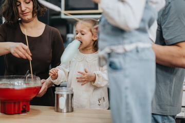 A scene of family members making and savoring cotton candy together at home. The warm and domestic...