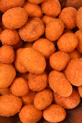 An extreme close-up, full frame shot of numerous orange, coated peanuts, showcasing their crunchy, textured surface
