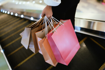 Close-up of a person holding multiple shopping bags in a mall, symbolizing retail therapy, consumerism, and modern lifestyle.