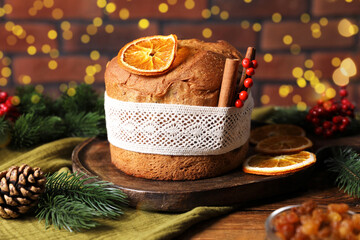 Christmas food. Delicious Panettone cake, ingredients and festive decor on wooden table against background with blurred lights, closeup. Bokeh effect