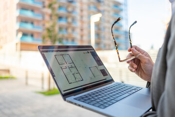 Architect checking apartment blueprint on laptop
