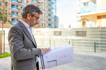 Professional architect examining blueprint on new construction site