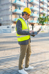Civil engineer typing on laptop at construction site
