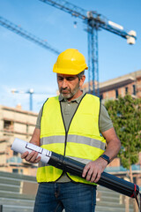 Engineer or architect inspecting blueprints at construction site