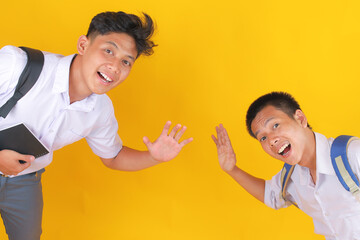 Cheerful Students Waving Hello With Backpacks in Bright Studio Light