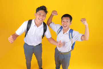 Cheerful Students Celebrating Graduation With Backpacks Against Bright Yellow Background