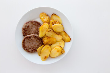 Hamburger e patate arrosto su piatto e tavolo bianco
